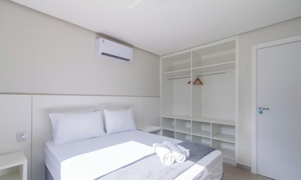 Een moderne hotelkamer met een net opgemaakt bed, een inbouwkleerkast en een wandgemonteerde airconditioner.