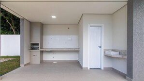 A modern outdoor kitchen area with a built-in oven, a sink, and a countertop. - Apart in Condo w/ Barbecue 700m From Beach Nvm0009 (Porto Seguro)