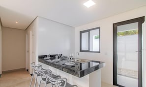 Een moderne keuken met een zwart aanrecht, witte wanden en een schuifdeur naar een balkon.