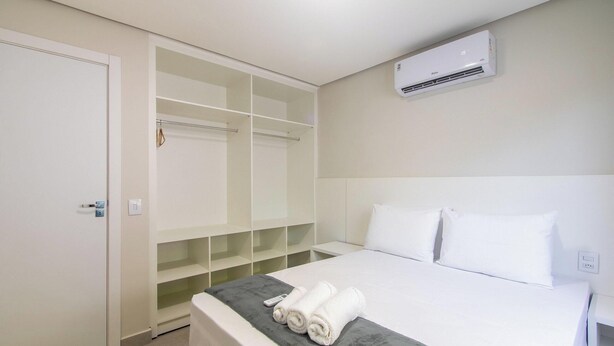 A hotel room with a bed, a wardrobe, and an air conditioning unit. - Apart in Condo w/ Barbecue 700m From Beach Nvm0009 (Porto Seguro)