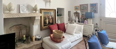 A living room with a fireplace, a sofa, a television, and a window.