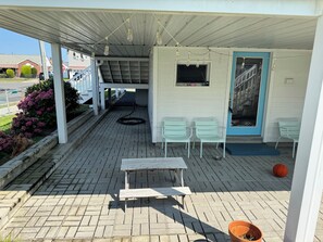 Ett takförsett utomhusområde med ett bord och stolar, en basketboll och en hund.