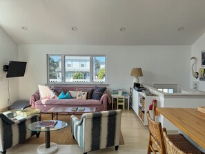 A modern living room with a sofa, armchairs, a coffee table, and a television mounted on the wall. - Bright and Sunny Beach House (Ventnor City)