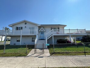 A two-story house with a blue door, a balcony on the upper floor, and a fenced front yard. - Bright and Sunny Beach House (Ventnor City)