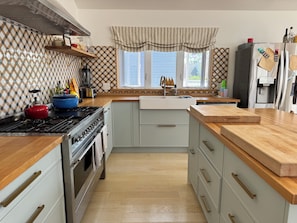 A kitchen with a stove, oven, and sink, wooden countertops, and a window with a view. - Bright and Sunny Beach House (Ventnor City)