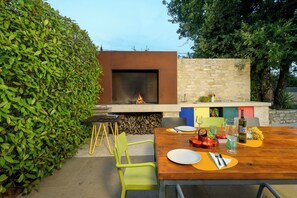 An outdoor dining area with a built-in fire feature, a stone wall, and a variety of seating and table settings. - Villa Casa LaBobina (Istria - Kurili) (Kurili)