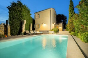 A swimming pool with lounge chairs and umbrellas, surrounded by greenery and a building with multiple windows. - Villa Casa LaBobina (Istria - Kurili) (Kurili)