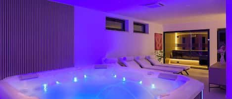 Un área de spa moderna con hidromasaje, sillones de masaje y un mostrador de recepción.