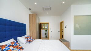 Un dormitorio moderno con una cama grande, un cabecero azul y un armario de madera.