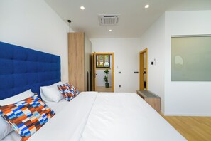 Ein modernes Schlafzimmer mit einem großen Bett, einer blauen Kopfteil und einem Holzschrank.