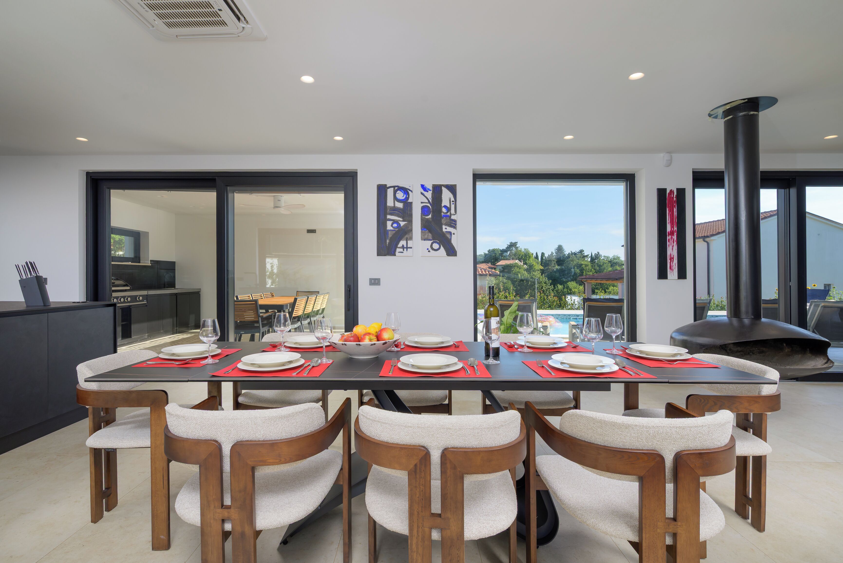 A modern dining area with a long table set for six, surrounded by chairs with cushioned seats.