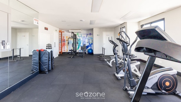 A gym with exercise equipment, a mirrored wall, and a colorful mural. - 2BR Apt w/ Self Check-in Nlv1107 (Curitiba)