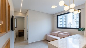 A modern, well-lit room with a large window, a built-in bench, and a marble countertop. - 2BR Apt w/ Self Check-in Nlv1107 (Curitiba)
