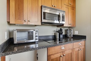 A kitchen with wooden cabinets, a stainless steel microwave, a toaster oven, and a coffee maker.