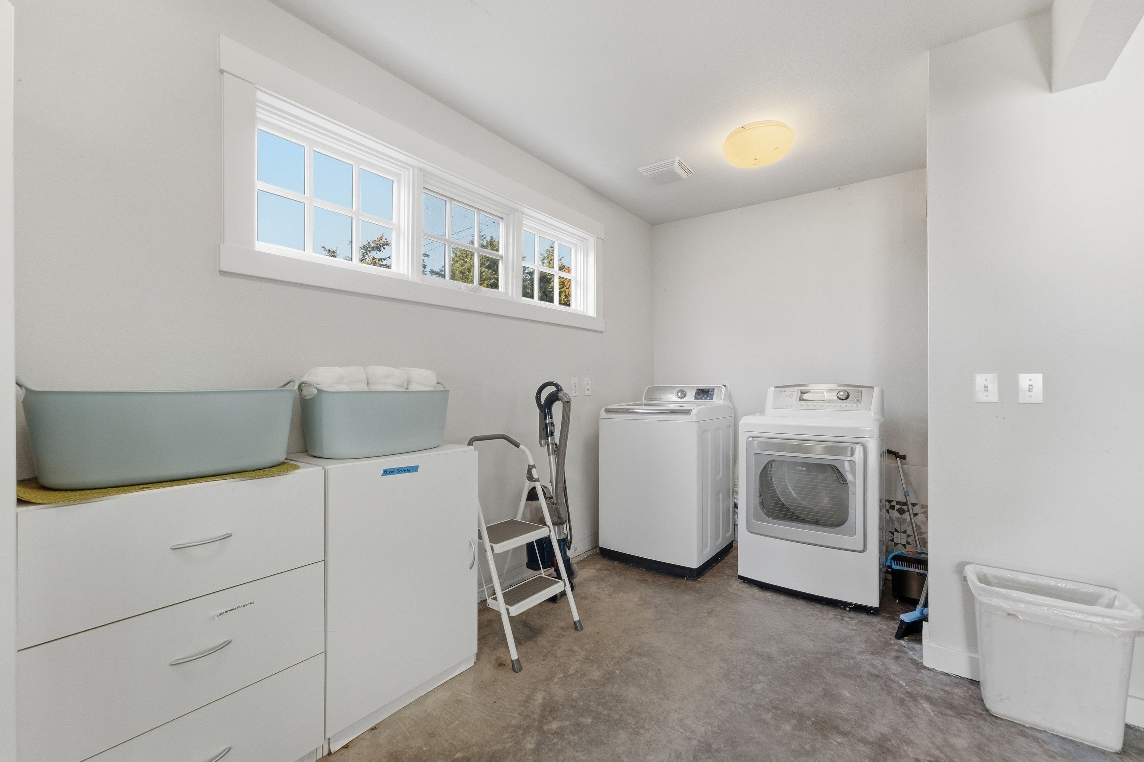 A laundry room with a washing machine, dryer, and a step stool.