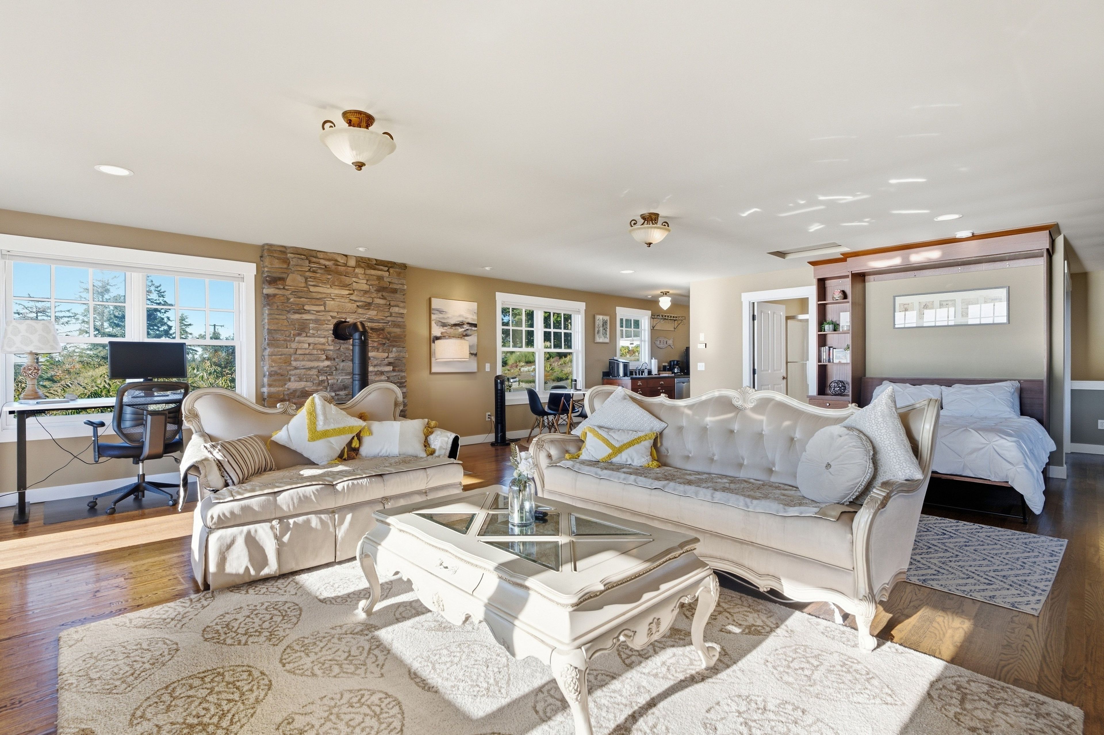 A spacious living room with a stone fireplace, a large sofa set, a coffee table, and a view of the outdoors.