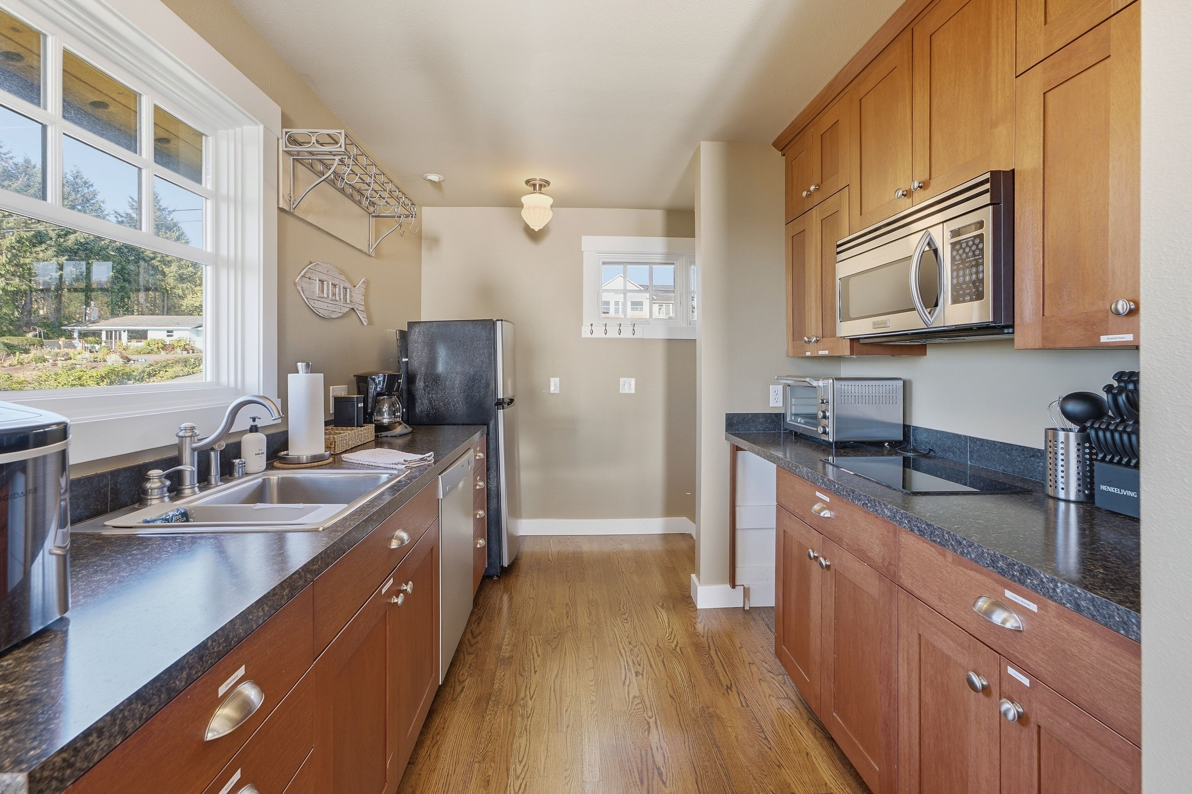 A modern kitchen with wooden cabinets, stainless steel appliances, and a view of the outdoors.