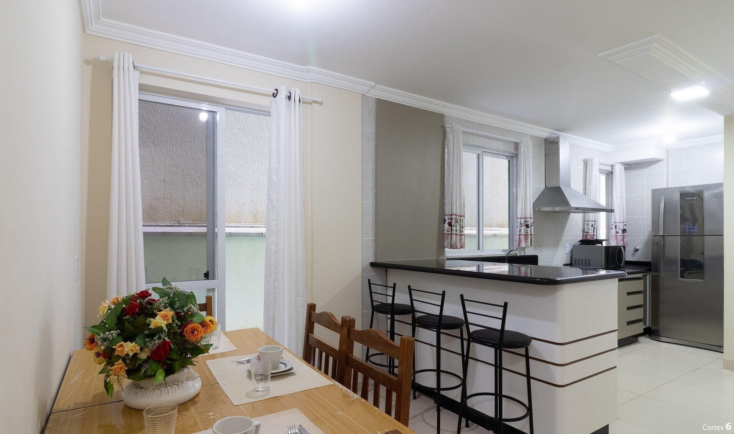 Una cucina moderna con isola centrale, zona pranzo con sedie e frigorifero.