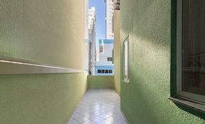 A narrow corridor with green walls and a tiled floor, leading to a window with a view of buildings. - Apt With Balcony & BBQ 78m From the Beach Obs0101 (Itapema)