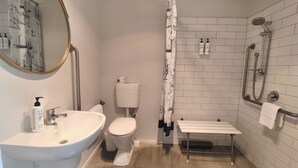 A bathroom with a sink, toilet, shower, and a mirror. - Easy Access Triple Studio Apartment with Alpacas (Rotorua)