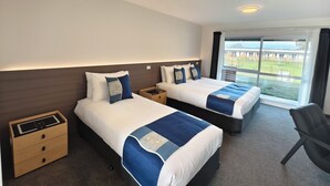 A hotel room with two beds, a desk, a chair, and a large window with a view. - Easy Access Triple Studio Apartment with Alpacas (Rotorua)