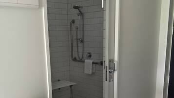 A bathroom with a shower, a towel rack, and a small table with towels.