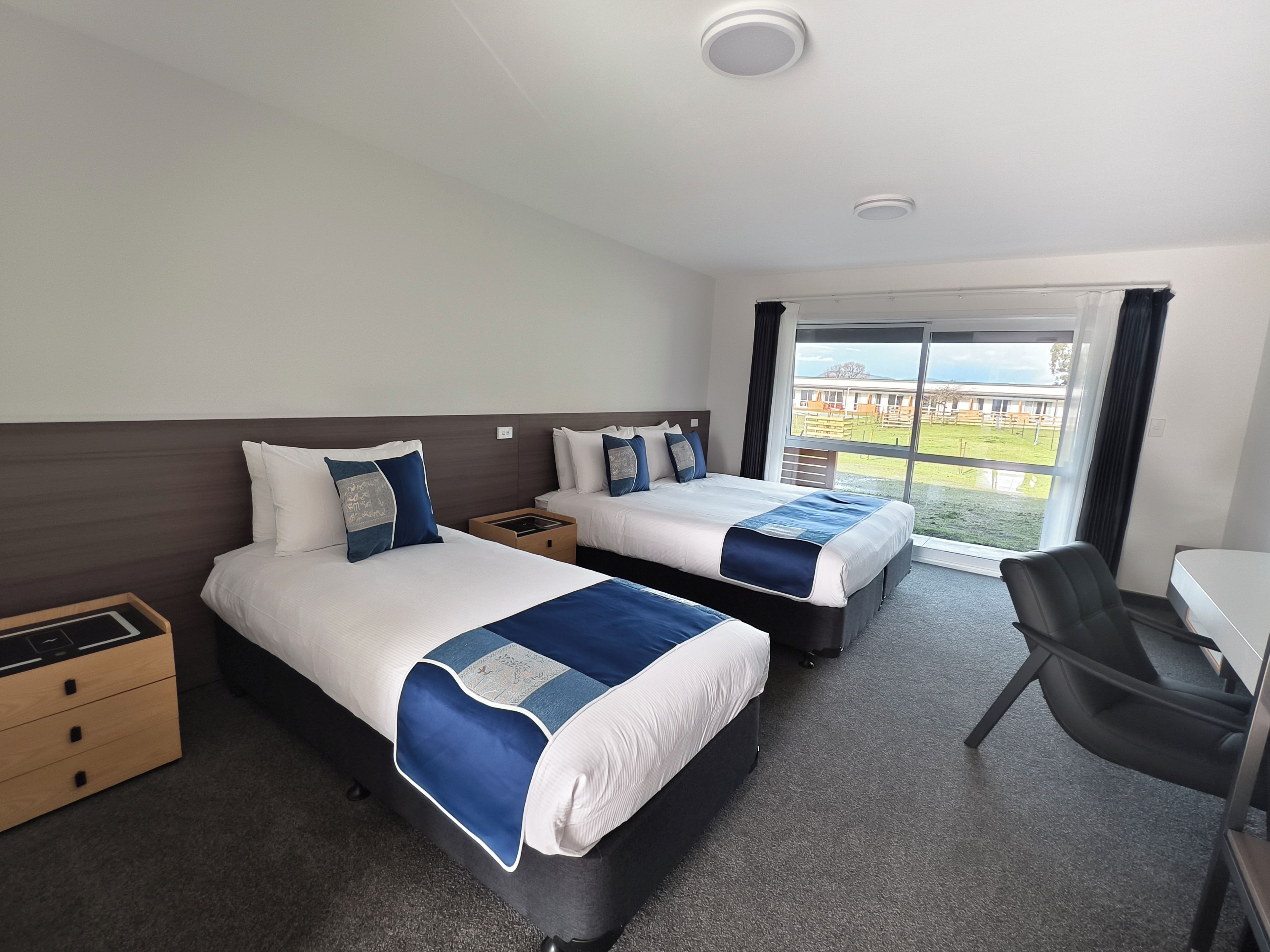 Une chambre d’hôtel avec deux lits, un bureau et une vue sur l’extérieur.