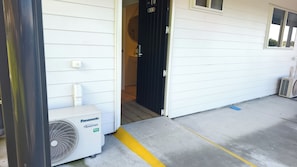Ein Gebäudeeingang mit einer weißen Tür, einem Panasonic-Inverter und einer Klimaanlage.