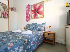 A bedroom with a bed, pillows, a bedside table with a lamp, and a wall-mounted TV. - Apartment 2380 by Interhome (Barbariga)