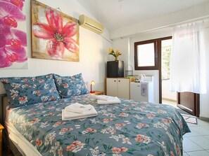 Een slaapkamer met een bed, een kaptafel, een raam en een schilderij aan de muur.