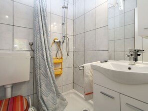 A modern bathroom with a shower, toilet, and sink. - Apartment 2380 by Interhome (Barbariga)