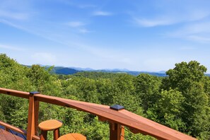 Eine Holzterrasse mit Blick auf eine bewaldete Landschaft und entfernte Berge.
