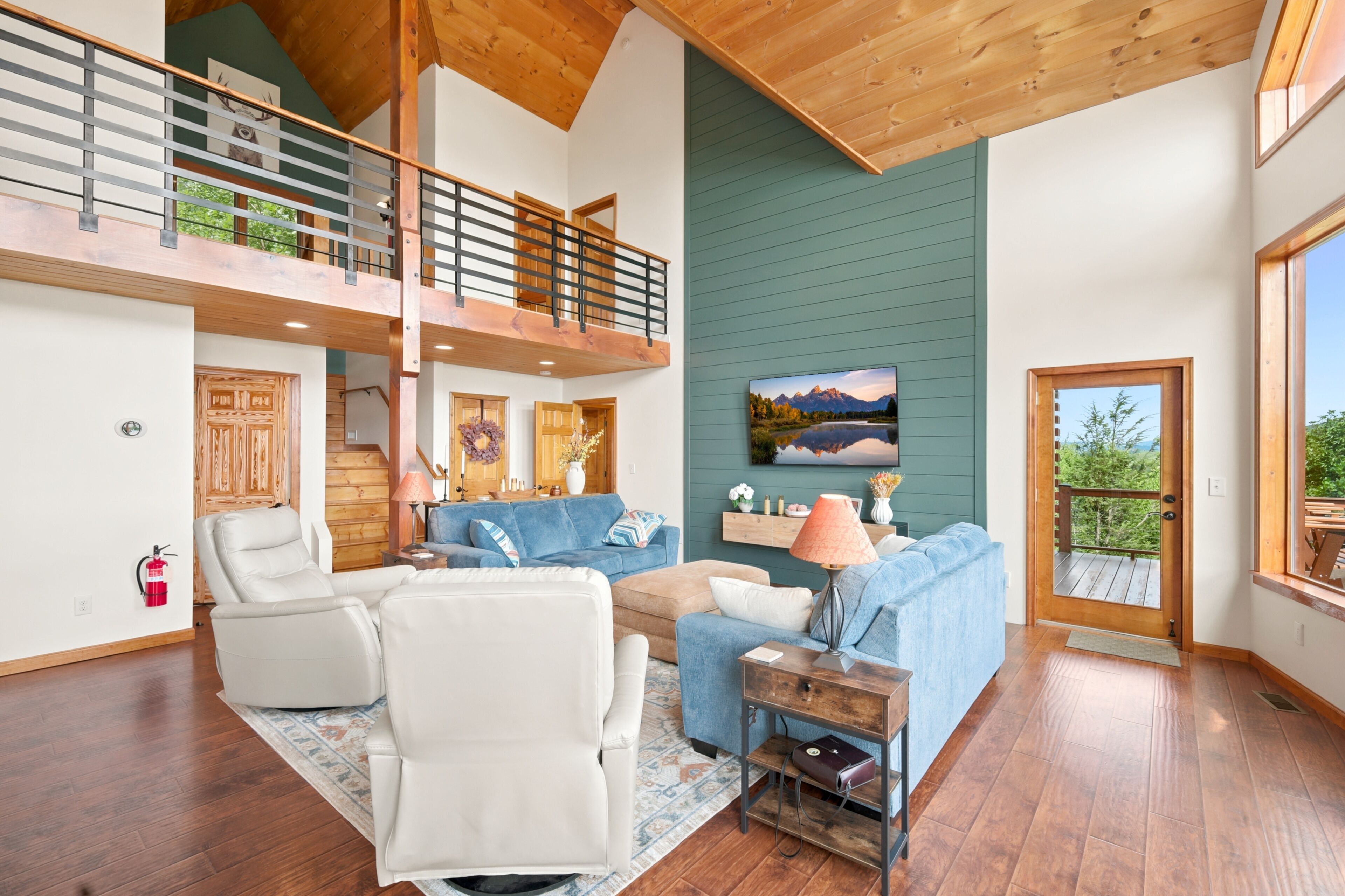 A spacious living area with a high ceiling, wooden beams, a blue sofa, a white armchair, and a fireplace.