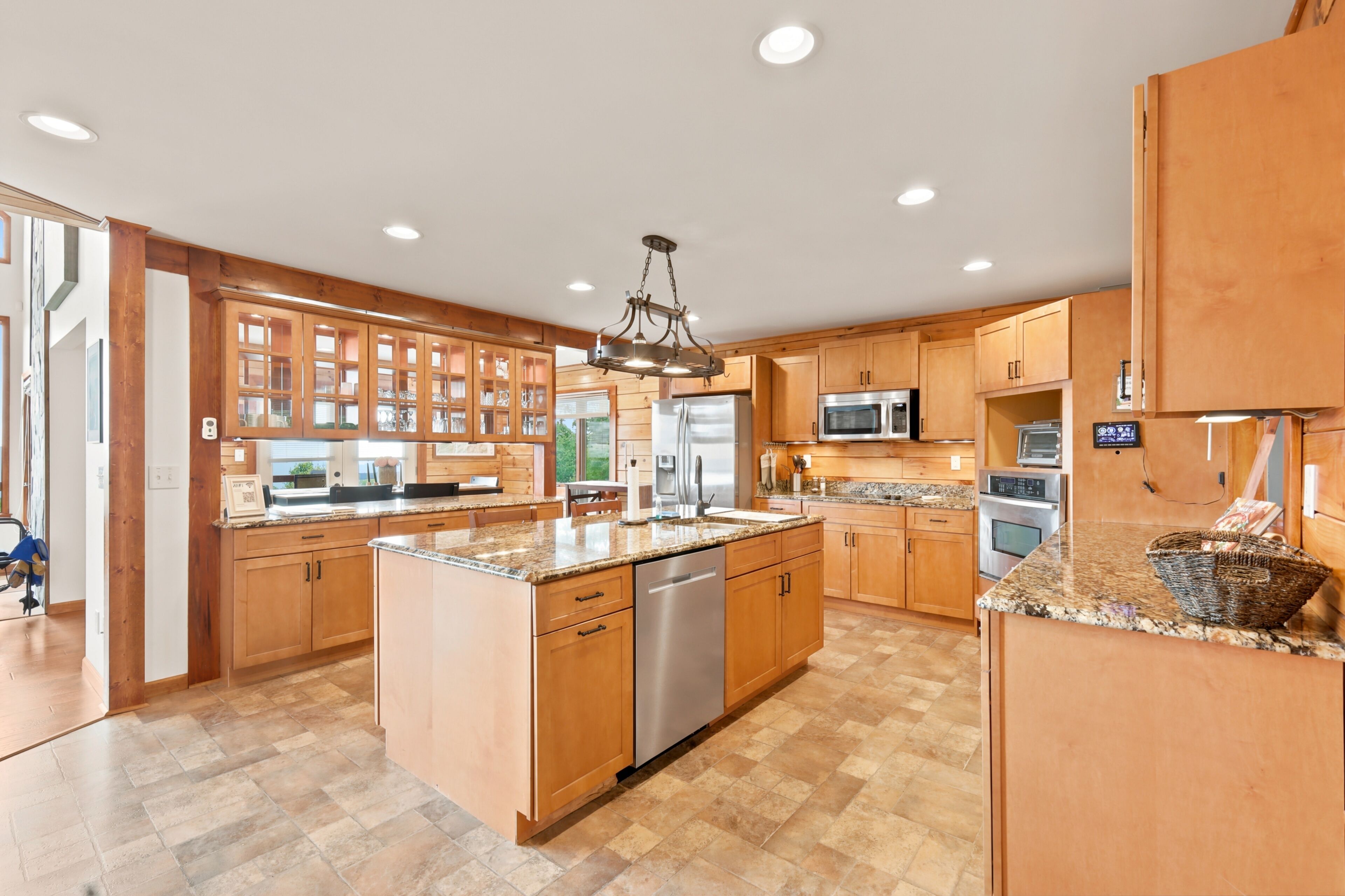 A spacious kitchen with wooden cabinets, granite countertops, stainless steel appliances, and a central island.