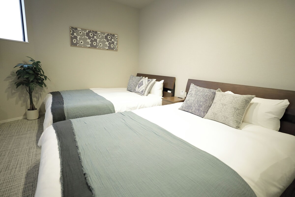 Ein Hotelzimmer mit zwei Betten, einer Topfpflanze und einer Wanddekoration.