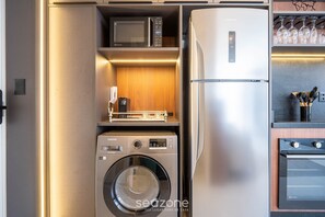 A compact kitchen with a built-in washer, microwave, refrigerator, and oven. - Studio in Cond. w/ Pool in Floripa Ogd0704 (Florianópolis)