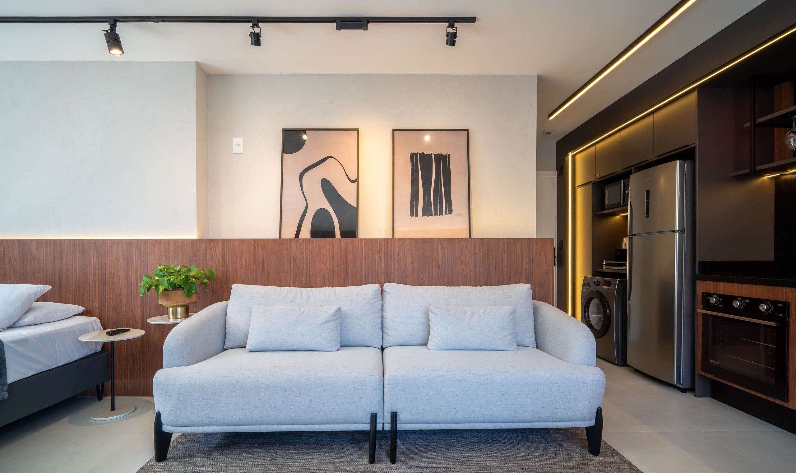 Un salon moderne avec un canapé gris, une petite table d’appoint ornée d’une plante et une grande œuvre d’art accrochée au-dessus du canapé.