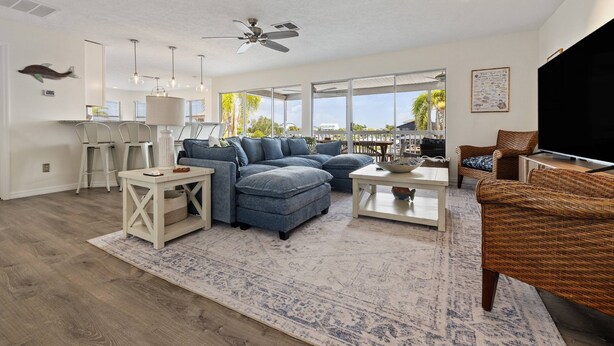 A modern living room with a sectional sofa, a flat-screen TV, and a dining area with a table and chairs. - 5BR, 3BA, Heated Pool, Game Room, Firepit, Boat Dock on Hernando Beach (Hernando Beach)