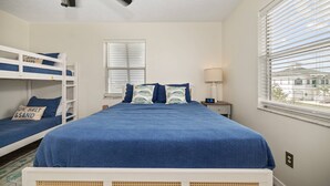 A bedroom with bunk beds, a bed with blue bedding, a bedside table with a lamp, and a window with blinds. - 5BR, 3BA, Heated Pool, Game Room, Firepit, Boat Dock on Hernando Beach (Hernando Beach)