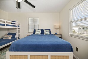 A bedroom with bunk beds, a bed with blue bedding, a bedside table with a lamp, and a window with blinds. - 5BR, 3BA, Heated Pool, Game Room, Firepit, Boat Dock on Hernando Beach (Hernando Beach)