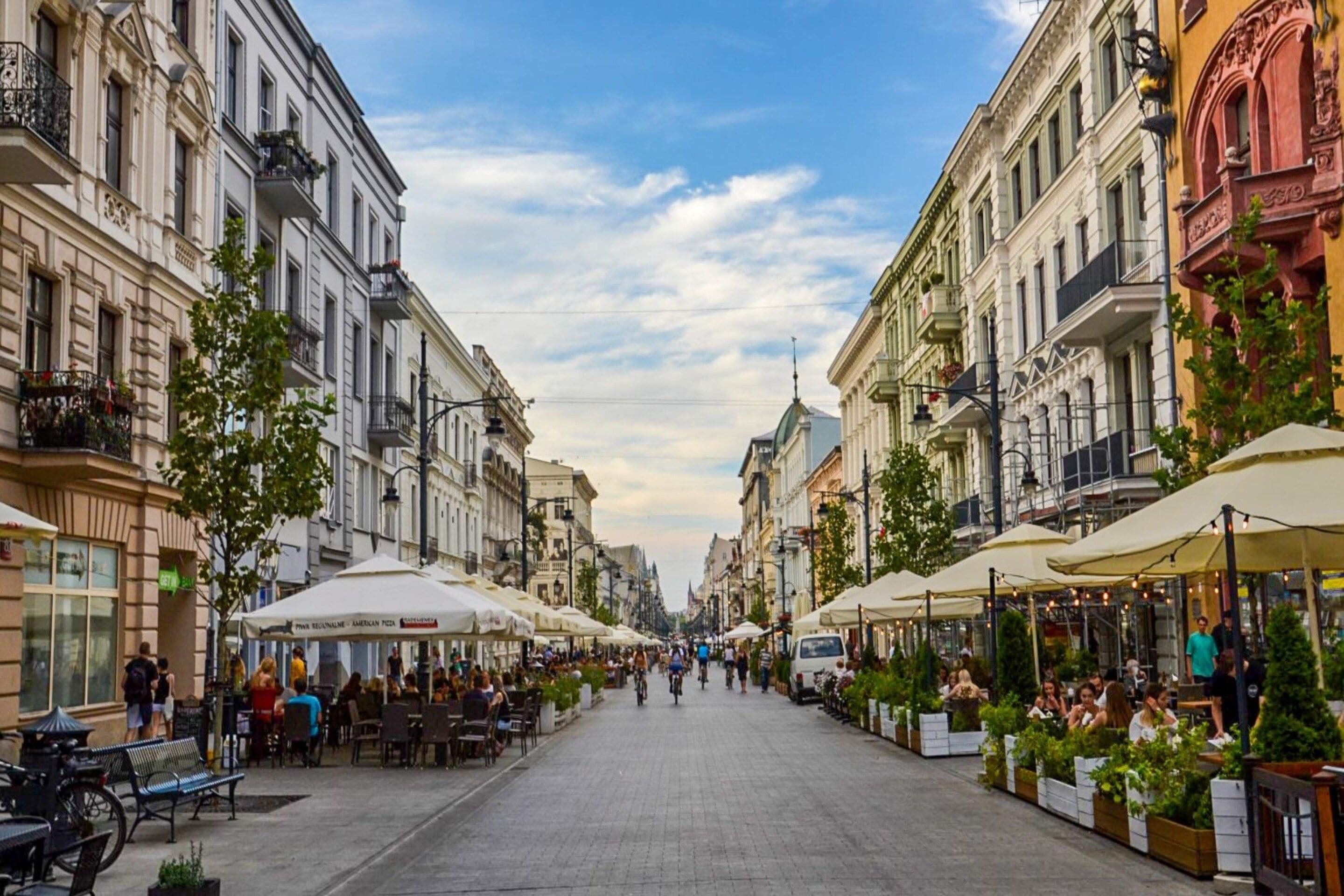 A street lined with cafes and outdoor seating, with pedestrians and parked bicycles.