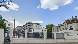 Ein geschlossenes Wohnkomplex mit moderner Architektur, darunter ein weißes Gebäude mit Balkonen und einem Backsteinkamin.