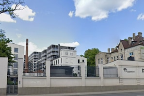 A gated residential area with modern and traditional buildings, a clear sky, and a tree in the foreground. - A Comfortable Apartment in the Center of Lodz (Łódź)
