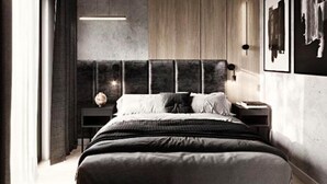 Ein modernes Schlafzimmer mit einem großen Bett, einem Nachttisch, einer Wandleuchte und einem gerahmten Bild.