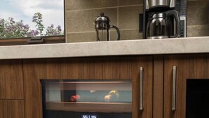 A kitchen with wooden cabinets, a built-in oven, and a coffee maker. - Signature Designer Home | Views, Wellness, Games (Sedona)