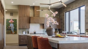 A modern kitchen with a large island, wooden cabinets, and a large window. - Signature Designer Home | Views, Wellness, Games (Sedona)