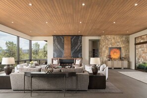 A spacious living area with a fireplace, stone walls, and a view of the outdoors. - Signature Designer Home | Views, Wellness, Games (Sedona)