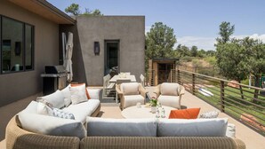 An outdoor patio with a sofa set, a grill, and a dining area. - Signature Designer Home | Views, Wellness, Games (Sedona)
