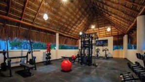 Een sportschool met een hoge nok, trainingsapparatuur en een grote rode trainingsbal.