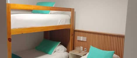 A bunk bed room with a ceiling fan, a nightstand, and a wall-mounted air conditioner.